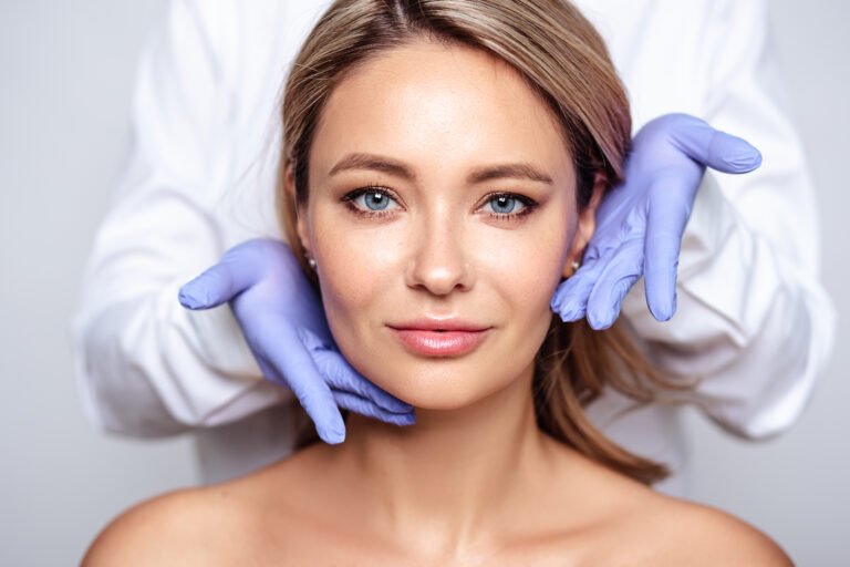 Specialist cu mănuși evaluează conturul facial al unei paciente la Wanderma Clinic
