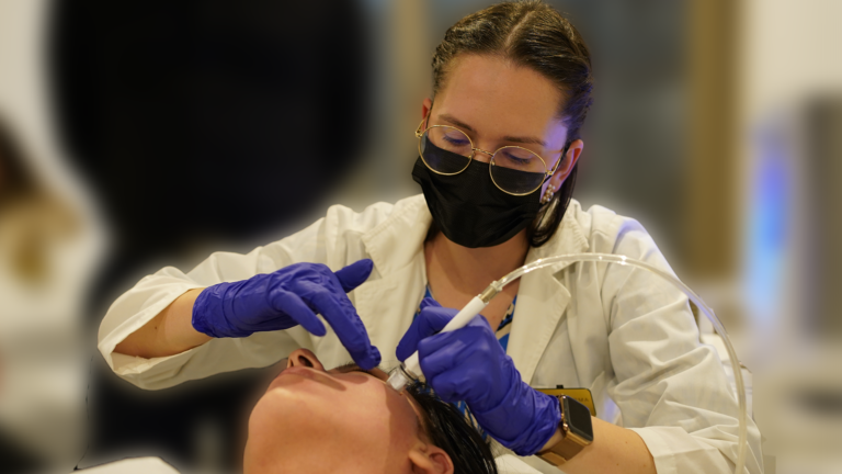 Membră a echipei Wanderma Clinic efectuând o procedură facială de curățare cu infuzie dermică.